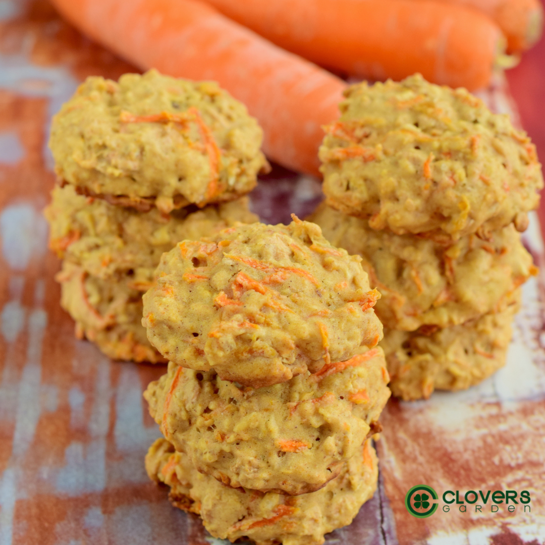 carrot cake drop cookies on a wooden board with whole carrots on the side.